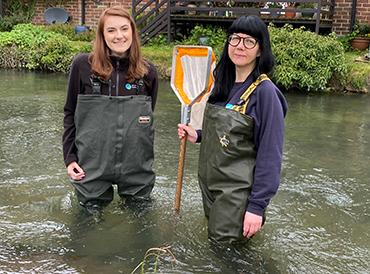 Alice Hope and Anna Forbes stand in the river Kennet