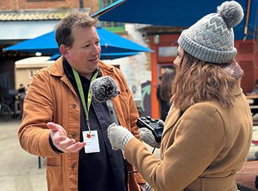 Josiah Meldrum (left) is interviewed by Alice Hope (right) who holds a microphone and recording device