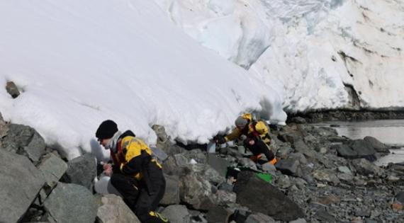 Two people sampling glacier meltwater 