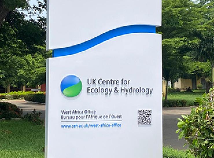 Pillar sign outside the UKCEH West Africa office, showing UKCEH logo and a QR code