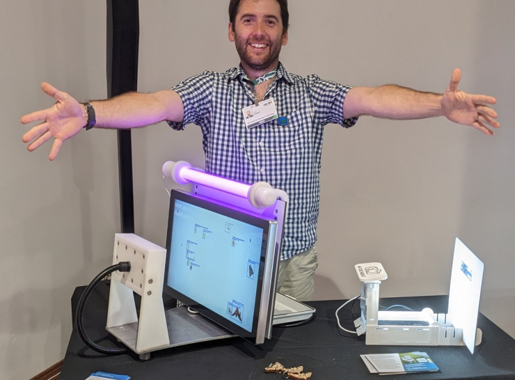 Tom August stands with his arms outstretched over a moth identification system