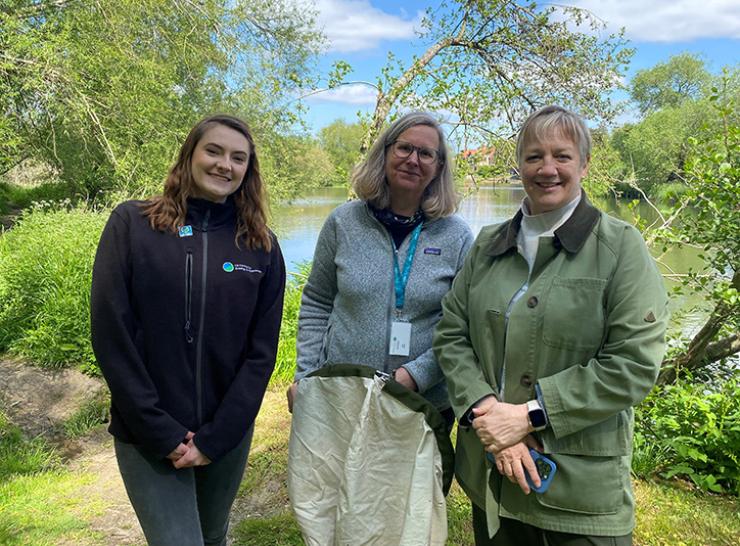 Group of three stand beside trees and a river